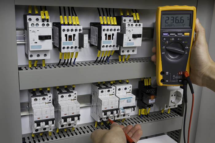 Electrician testing a switch board with a meter